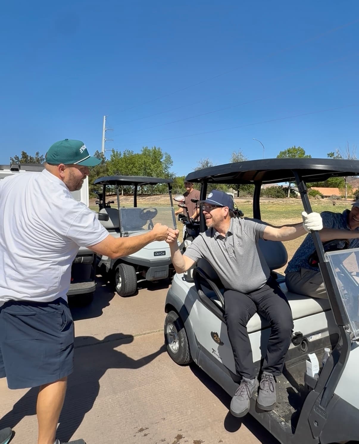 Physicians fist-bumping on the golf course at a Clubs & Scrubs event