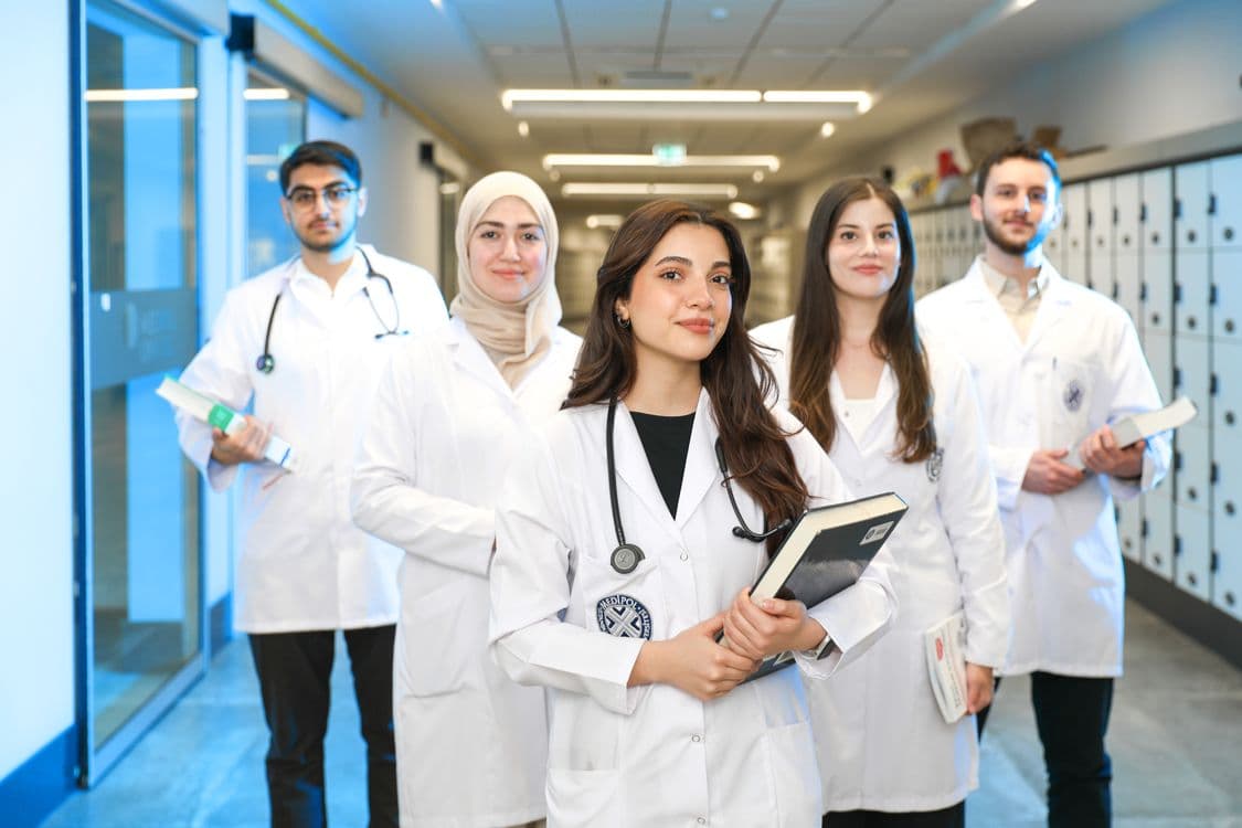 Medical student in white coat with anatomy reference — medical school program