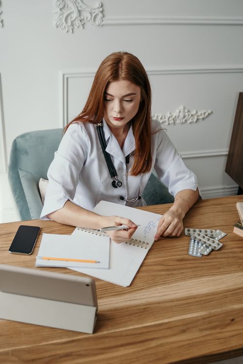Physician at desk reviewing notes and professional resources
